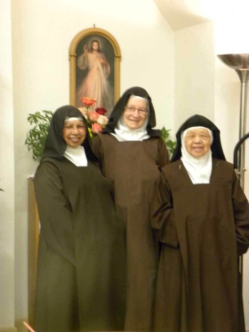 Three nuns in brown robes posing for a picture.