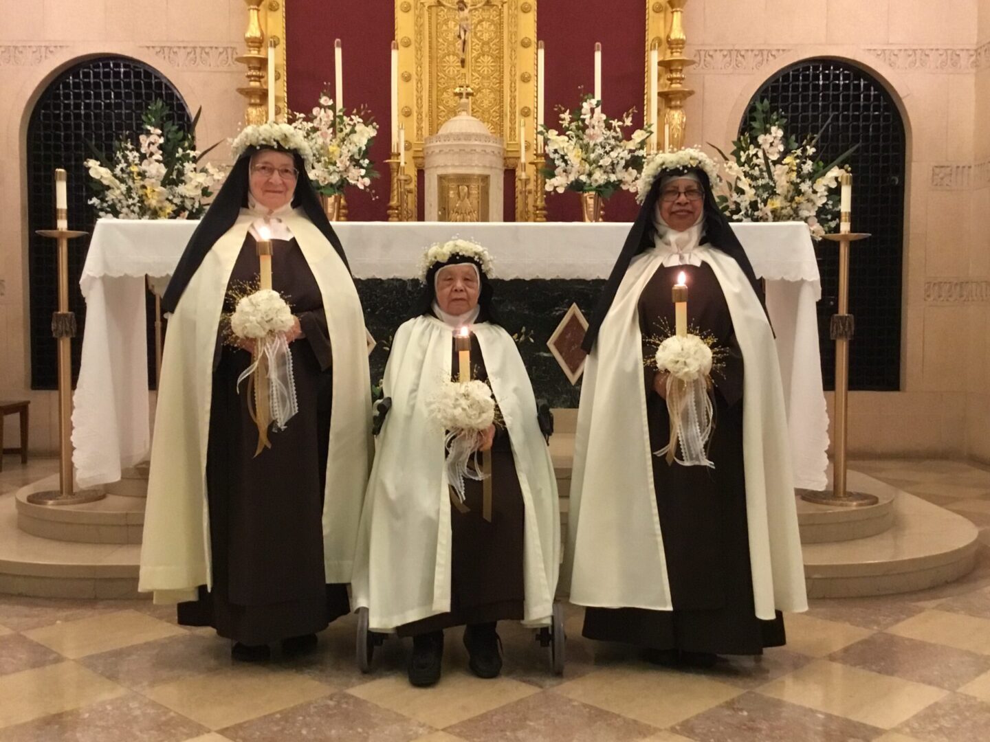 Three nuns standing in front of a church alter.