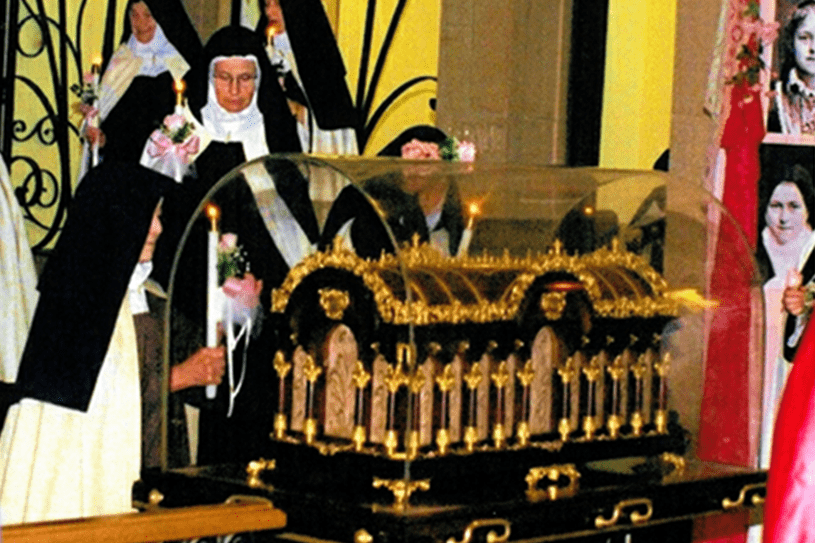 Nuns standing near an ornate religious relic display in a church.